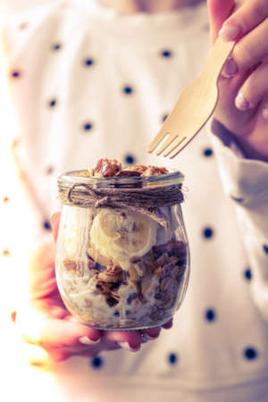 Female hands, woman eating Healthy breakfast. Oatmeal Granola with greek yogurt and nuts banana...
