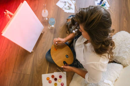 Creative painter in working process. Artist workplace, hobby, craft tools. Artist female canvas...