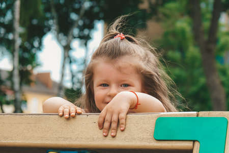 Kid on obstacle course. Pretty happy young girl playing outside in playground. Portrait Of Cute Girl Playing At Playground. Happy childhood. Playtimeの写真素材