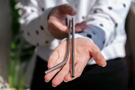 Woman holding Reusable Metal Straw. Female Hand on reusable collapsible drinking straw. Eco...