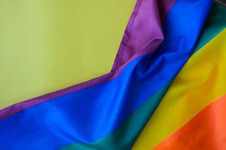 Rainbow flag on yellow background with copy space. Rainbow lgbtq flag made from silk material....
