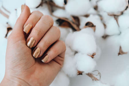 Manicured female hands with stylish golden nails. Trendy modern design manicure. Gel nails. Skin care. Beauty treatment. Nail care. Wellness. Trendy colors.の写真素材