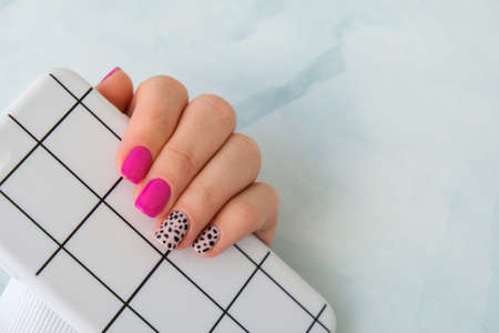 Manicured female hands with stylish green nails holding mobile phone. Smartphone technology. Trendy modern design manicure. Gel nails. Skin care. Beauty treatment. Nail care. Wellness. Trendy colors.の写真素材