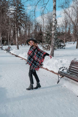 Young woman enjoying winter weather in the snow park. Cold weather. Winter fashion, holidays, rest,...