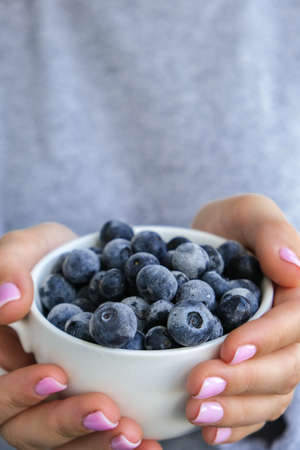 Woman holding bowl with Frozen blueberry fruits. Harvesting concept. Female hands collecting berries. Healthy eating concept. Stocking up berries for winter Vegetarian vegan food. Dieting nutritionの写真素材