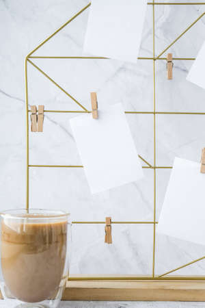 White home office room interior, bloggers workplace. Cup of coffee. Mood board with postcards and reminders mockup. Cotton branches in a vase, interior decoration. Freelance workplaceの写真素材