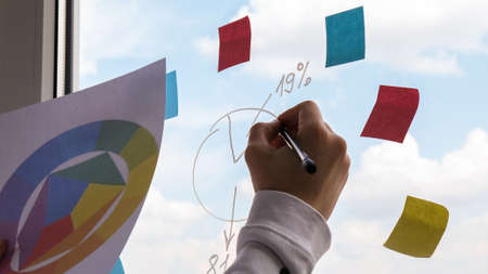 Female interior designer holding color palette in office. Workplace Workspace window. Architect at work. Colorful pie chart and graphの写真素材