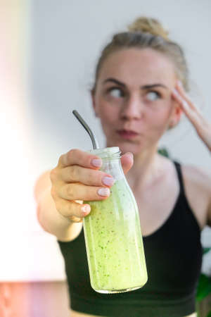 Young millenial blond woman drinking vegan smoothie drink detox. Woman doing yoga exercises at home. Clean eating, weight loss, healthy dieting food concept. Stay healthyの写真素材