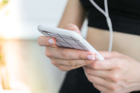 Modern gadgets for training at home. Woman using fitness app on smartphone indoors at home. Fitness tracker and smartphone in hand. Headphones sport watch. Workout and Fitness lifestyle concept. Online tuition. Wellbeing exercisesの写真素材