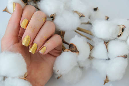 Manicured female hands with stylish golden nails. Trendy modern design manicure. Gel nails. Skin...