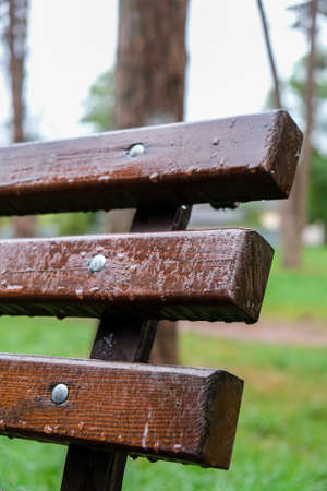 Wet bench in the park in the rain. Rainy weather. Wooden chair in the rain. Wet urban furniture....