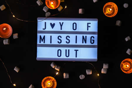 Lightbox with text JOMO Joy of Missing Out. The concept of relaxation from information and gadgets. Top view. Flat lay. Tea light candles. Digital detoxの写真素材