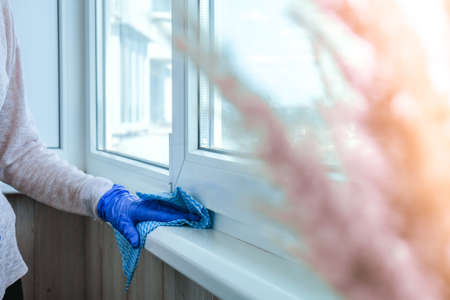 Cleaning the windowsill wiping dust by blue microfiber cloth for cleaning on the glass window rail...