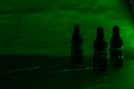 Various glass bottles with CBD oil, THC tincture. Vape concept. Light effects. Medicinal cannabis with extract oil in a bottle. Healthcare conceptの写真素材