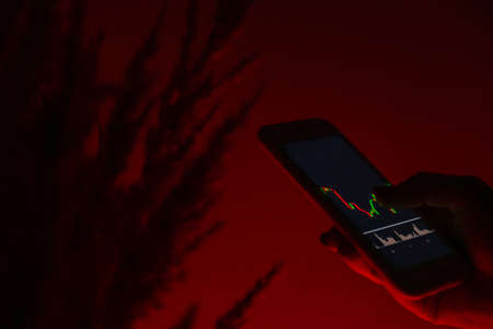 Stock market graph for tranding and investment in security exchange. Woman holding phone Show the stock index screen. Stock market investment concept Accounting Finance.の写真素材