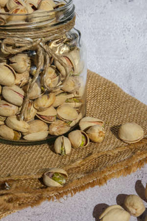 Pistachios in glass jar on concrete background. Organic pistachios, healthy food. Heap or stack of pistachios. Vegan omega nutrition. Roasted salted pistachios.の写真素材