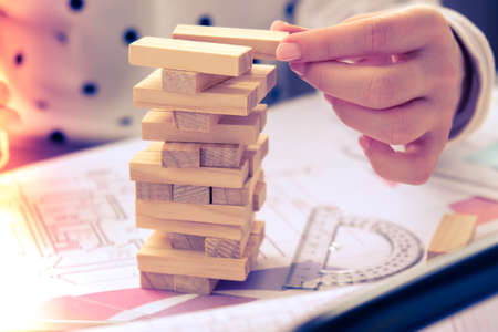 Architect designer Interior creative working hand playing a block wood game on desk architectural plan of the house, a color palette. Female architect drawing blueprints in office workplace. Workspaceの写真素材