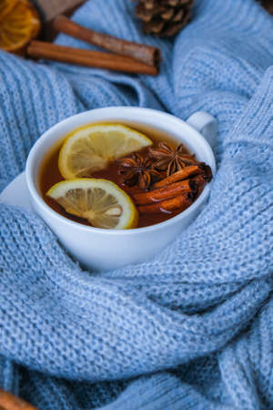 Blue sweater and cup of hot tea with lemon cinnamon sticks and anise star. Dry slices of citrus orange and cones. Hot winter cocktail. Christmas, Thanksgiving drinks. Autumn, grog, hot sangria, mulled wine. Festive holiday flat lay atmosphereの写真素材