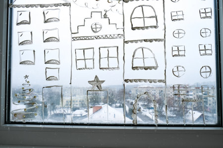 christmas holidays decoration painted on window glass. New Years scenery. city buildings garlands...