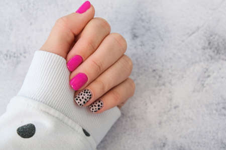 Manicured female hands with stylish pink nails and design. Trendy modern design manicure. Gel nails....