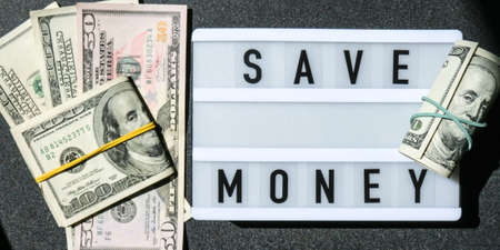 Lightbox board with word SAVE MONEY in black letters around US dollar banknotes. Money, Business, finance, investment, saving. Cash bill. Business budget of wealth and prosperity finance. Passive incomeの写真素材