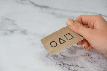 Kiev Ukraine - October 2021 Hand holding a squid game invitation card. Symbol of Squid Game...