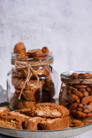 Traditional Italian cantuccini cookies with almonds in glass jar. Sweet dried biscuits. Homemade fresh Italian cookies cantuccini stacks and organic almond seeds. Healthy organic eatingの写真素材