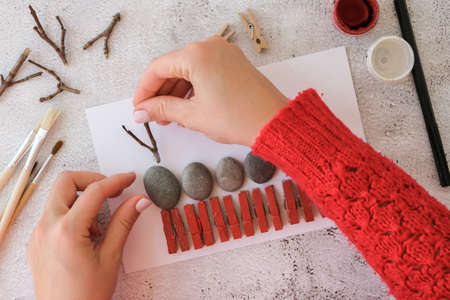 Diy Merry Christmas deer on greeting card postcard made of pebbles, sea stones, clothespins and branches on white background. Natural Eco style diy. Gift idea. Step by step. Top view.の写真素材