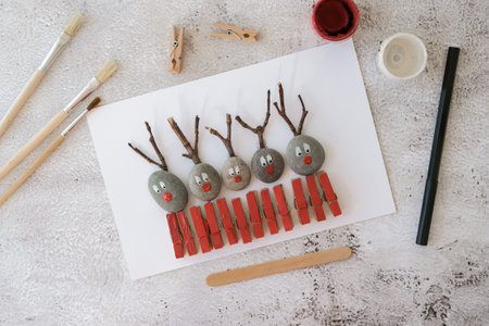 Merry Christmas deer on greeting card postcard made of pebbles, sea stones, clothespins and branches on white background. Diy Natural Eco style diy. Gift idea. Step by step. Top view.の写真素材