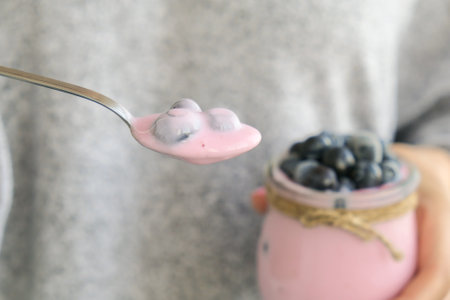 Female hands holding Bowl with yogurt and blueberries on table. Woman eating Blueberry yogurt with fresh blueberries. Healthy breakfast. Super food healthy eating vegetarian vegan foodの写真素材