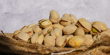 Pistachios in burlap sack on concrete table. Organic pistachios. Vegan Healthy food high protein....