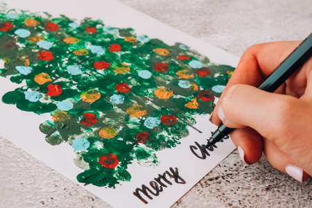 DIY Making greeting card Handmade crafts on holiday for children. Paint with fingers Merry Christmas...