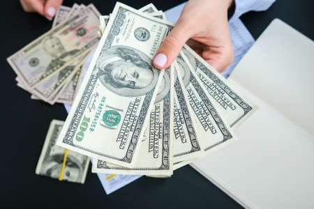 Business Woman Displaying a Spread of Cash US dollars. Close-up. Income and Business concept. Venality, bribe, corruption concept. Hand giving money. Millennial candid authentic female hands counting money usd. Business budget of wealth and prosperity financeの写真素材