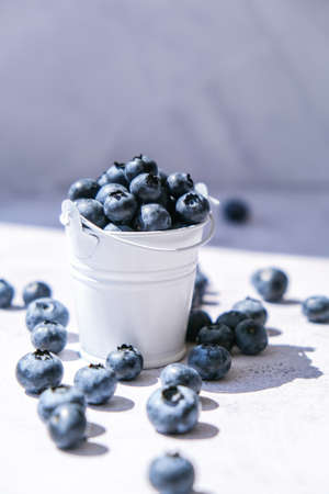 Blueberries in a small Bucket on concrete background. Healthy organic seasonal fruit background....