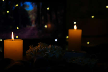 Movie on laptop at night in bedroom lit with candles. Pop corn. Autumn atmosphere at home. Cozy...