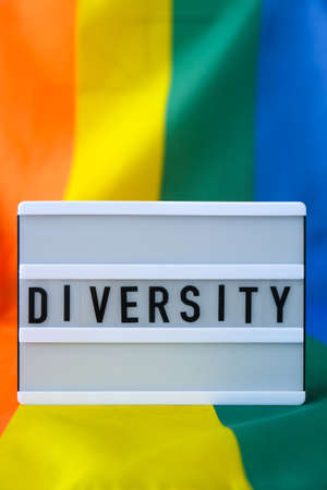 Rainbow flag with lightbox and text DIVERSITY. Rainbow lgbtq flag made from silk material. Symbol of LGBTQ pride month. Equal rights. Peace and freedomの写真素材