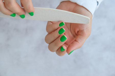Manicured female hands with stylish green nails. Trendy modern design manicure. Gel nails. Skin care. Beauty treatment. Nail care. Trendy colors. Manicure toolsの写真素材