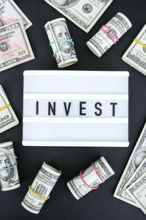 Lightbox board with word INVEST in black letters around US dollar banknotes. Money, Business, finance, investment, savingの写真素材