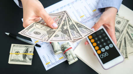 Kiev, Ukraine - May, 2021. Millennial candid authentic female hands counting money usd. Businesswoman hands count abundance one hundred dollar banknotes usa. Pile capital of American US dollars bills notes cash. Business budget of wealth and prosperity finance. Lockdown covid-19, franklin face, buy coin, economic, exchange payday. Symbol tax transaction president profit messy income illegal currencyの写真素材