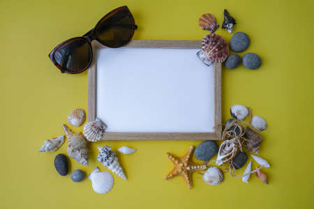 Composition frame for copy space, seashells, pebbles, mockup on yellow background. Blank, top view, still life, flat lay. sea vacation travel concept tourism and resorts.の写真素材