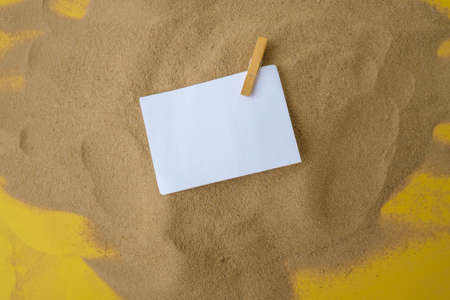 Sheet of white paper with copy space clothespin on sand. Summer vacation holiday concept. Planning trip. Sea time Advertising promotion mock upの写真素材