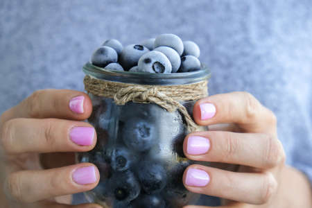Woman holding bowl with Frozen blueberry fruits. Harvesting concept. Female hands collecting berries. Healthy eating concept. Stocking up berries for winter Vegetarian vegan foodの写真素材