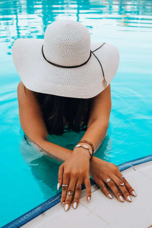 Portrait beautiful young caucasian woman in hat relax smile leisure around outdoor swimming pool....