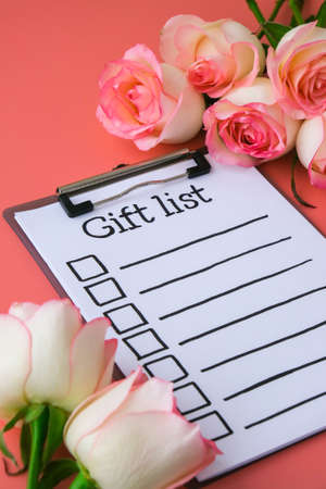 GIFT LIST on paper note. Delicate pink roses on pink background. Minimal trendy composition....
