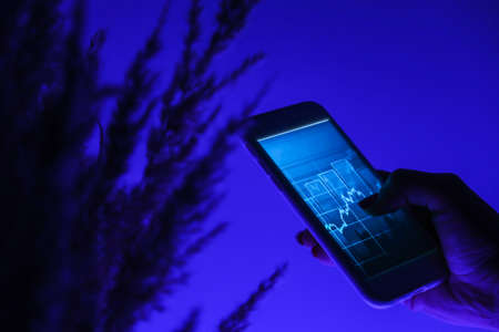 Woman holding mobile phone, block chain with graph of stock market background, cryptocurrencies or bitcoin concept. Night blue light. Futuristic stock exchangeの写真素材