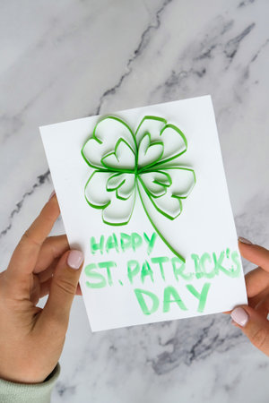 Diy St. Patricks Day greeting card made of Quilling and paper clovers on white background. Gift...