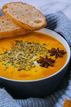 Homemade carrot ginger curcuma spicy soup. Seasonal Pumpkin traditional soup with creamy silky texture in cozy sweater background. Healthy vegan clean eating.の写真素材
