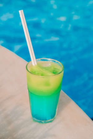 Drinking cocktail on vacation next to the swimming pool. Color fruit detox smoothie. Summertime vacation holidays.の写真素材