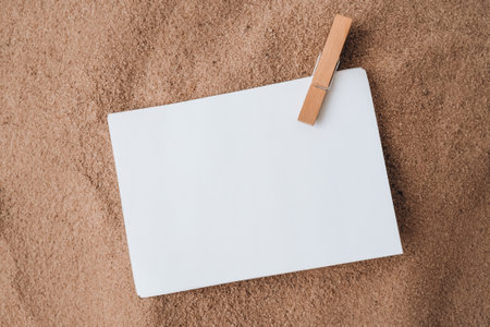 Sheet of white paper with copy space clothespin on sand. Summer vacation holiday concept. Planning trip. Sea time Advertising promotion mock upの写真素材