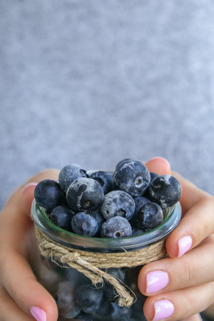 Woman holding bowl with Frozen blueberry fruits. harvesting concept. Female hands collecting...